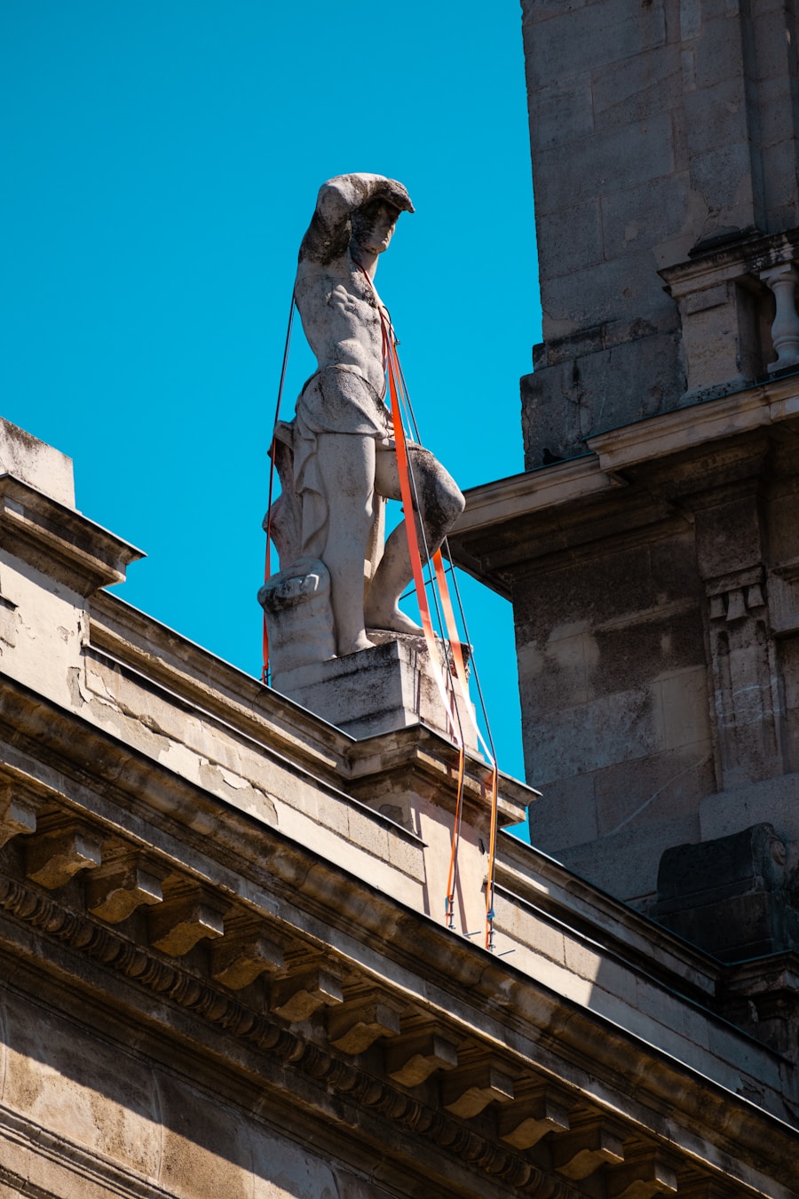 A statue atop a historic building under restoration
